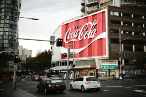 Sydney's famous Coca-Cola billboard lights up a busy street corner.