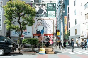 A vibrant street scene in Tokyo Japan featuring colorful billboards and pedestrians on a sunny day.