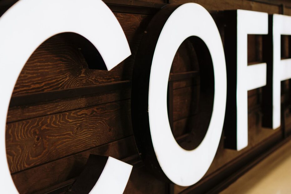 A close-up view of a large, illuminated coffee sign with wooden background indoors.