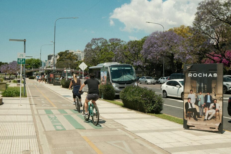 Urban cyclists on a sunny day surrounded by blooming jacaranda trees and active traffic.