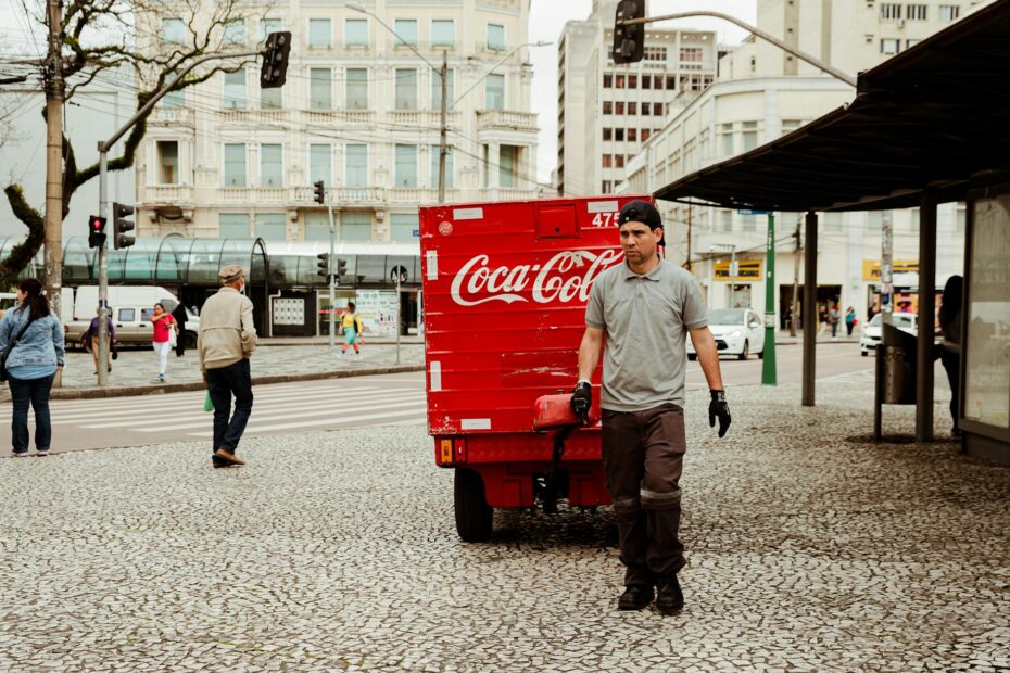 Street scene with a worker pulling a Coca-Cola cart in an urban setting.
