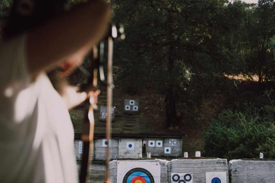 Focused archer aims at colorful targets in an outdoor forest range.