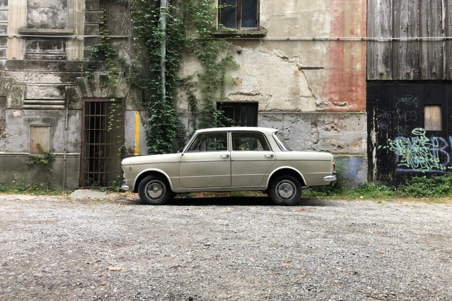 A classic beige Fiat sedan parked in a rustic alleyway in Como, Italy.
