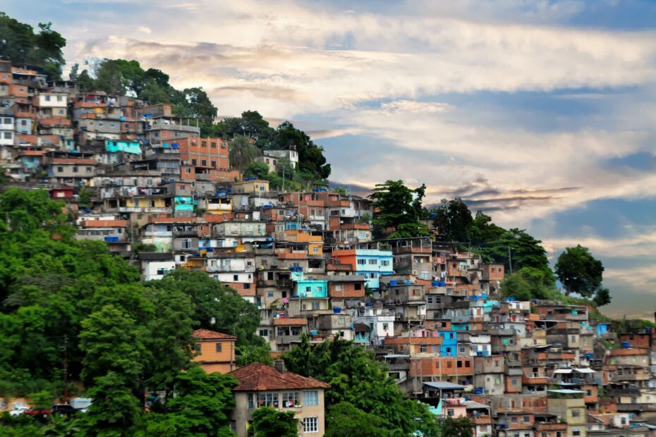A colorful hillside favela with diverse architecture under a vibrant sky, showcasing urban life.
