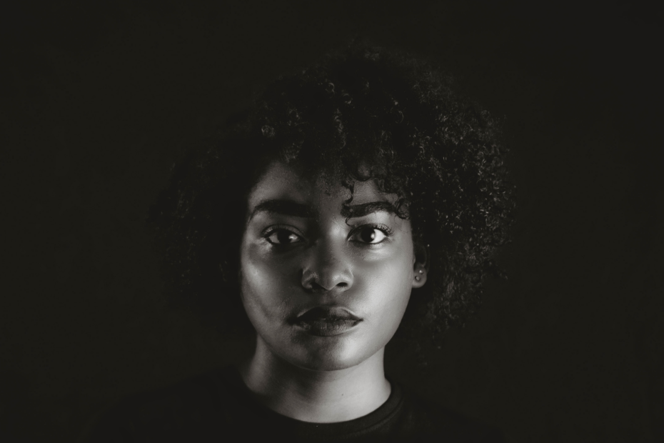 Captivating black and white portrait of an African woman with curly hair, evoking a moody aesthetic.