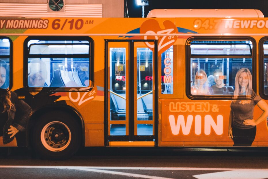 A vibrant public transport bus with advertisements, captured at night under streetlights.