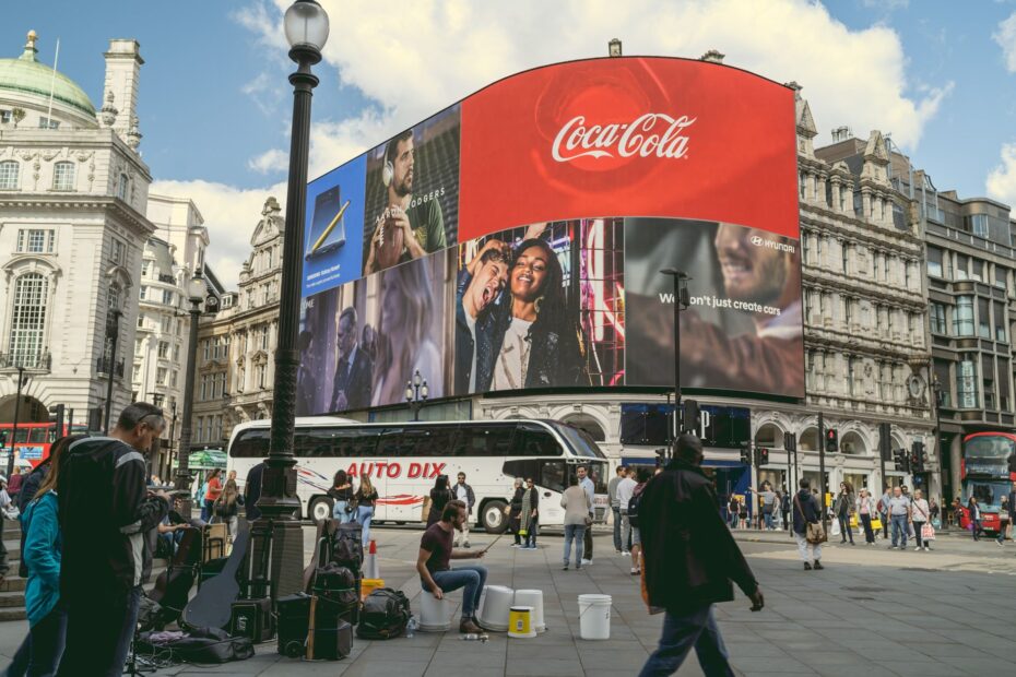Tourists and buskers at Piccadilly Circus under iconic billboards in London, a center of urban life and commerce.