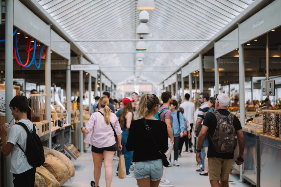 People exploring a vibrant indoor market with modern architecture and diverse stalls.