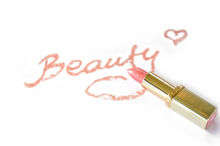 Close-up of pink lipstick next to 'Beauty' written on paper with a heart.