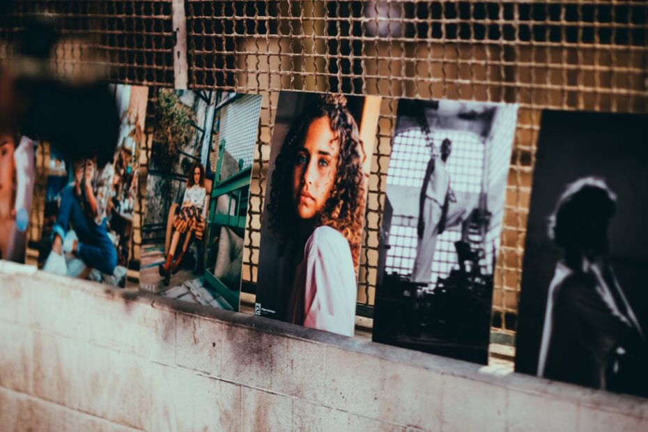 A collection of diverse artistic portraits displayed along a textured wall in Rio de Janeiro.