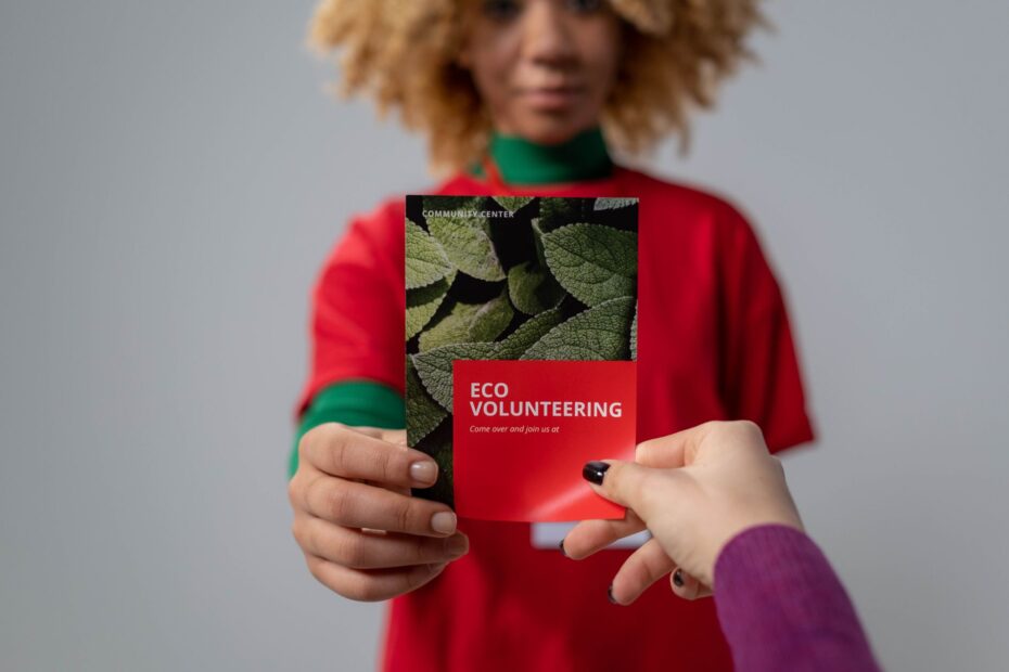 Close-up of hands exchanging an eco volunteering brochure, representing environmental awareness.