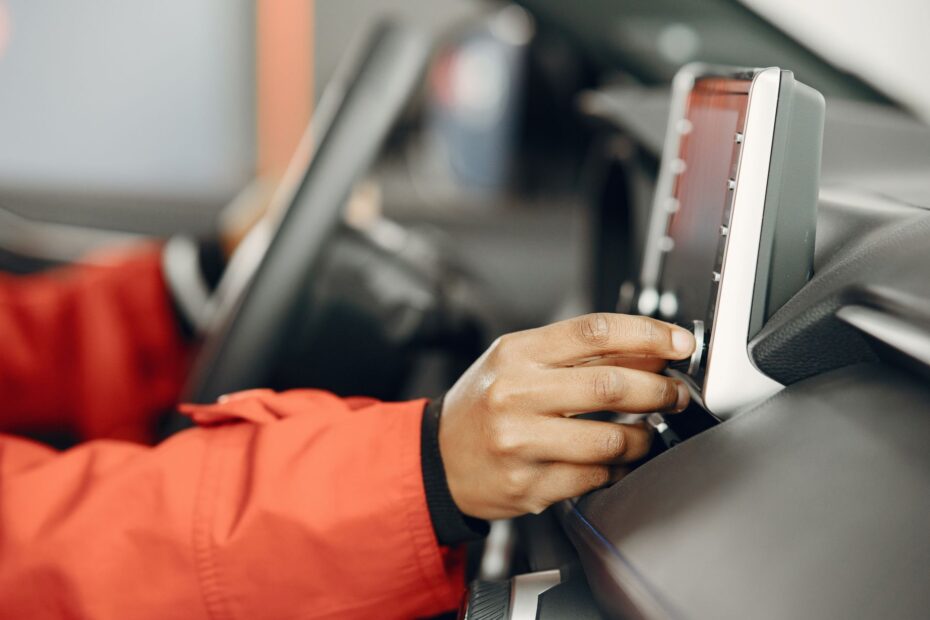 Close-up of a hand adjusting the car stereo while driving, highlighting technology and focus.