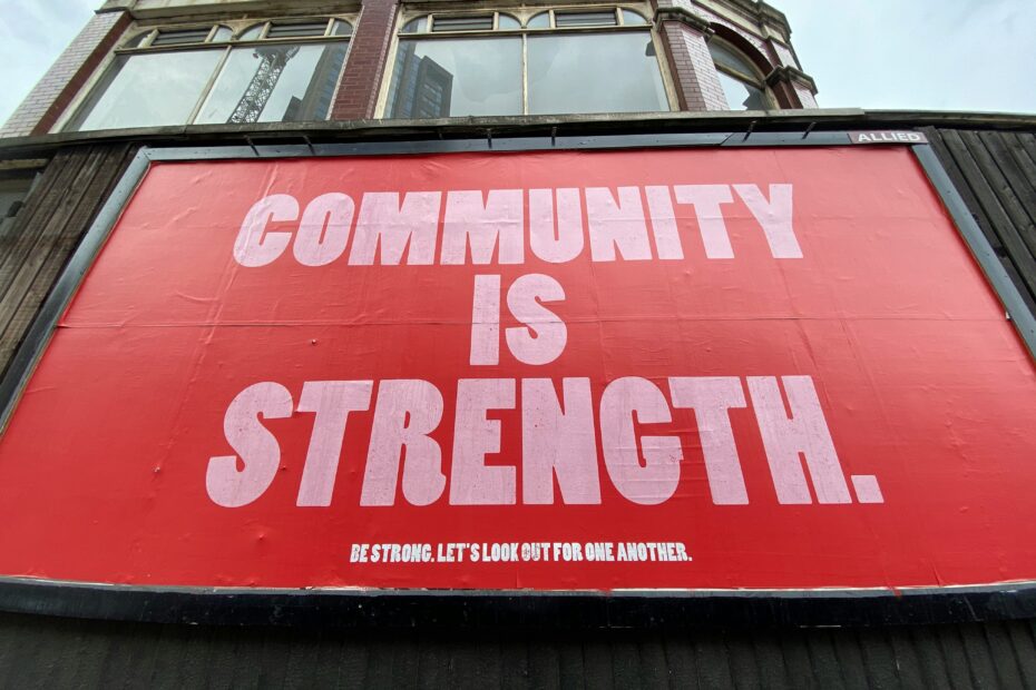 A large red billboard with white text reading COMMUNITY IS STRENGTH on a building